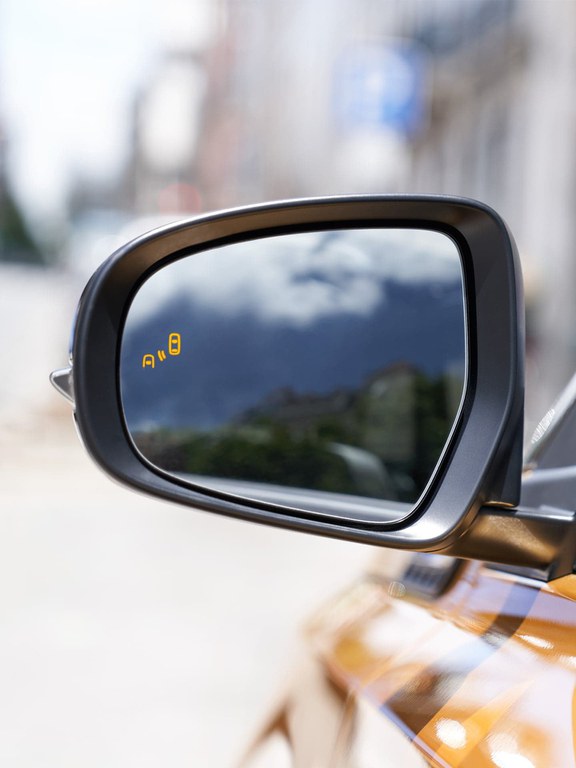 Detailaufnahme des linken Seitenspiegels eines Suzuki Vitara Hybrid in Solar Yellow Pearl Metallic.