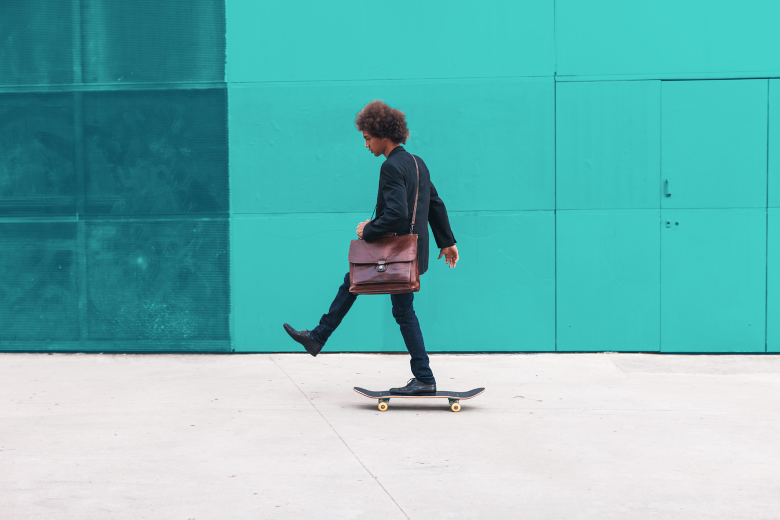 Ein junger Mann fährt auf einem Skateboard von rechts nach links. Vor dem Bild ist ein hellblauer Filter.